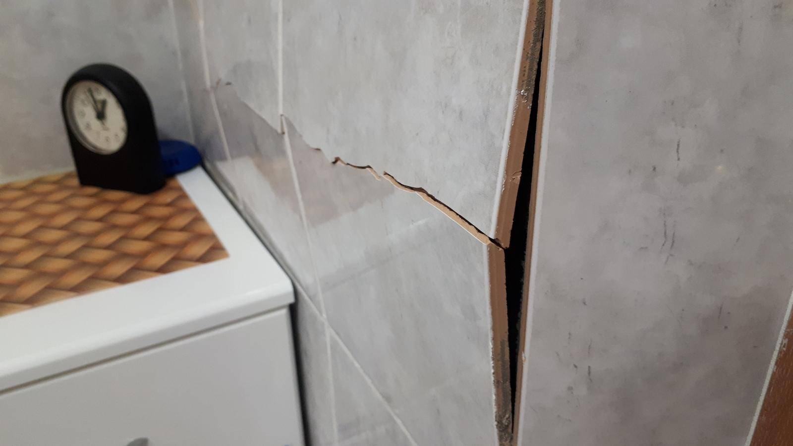Трещины в ванной. Плитка треснула на стене. Треснула плитка на стене в ванной. Плитка отваливается от стены. Отвалившаяся плитка.
